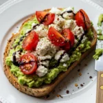 Delicious avocado toast recipe topped with creamy feta cheese and juicy sliced tomatoes, ready in 15 minutes.