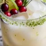 Creamy coconut margarita with lime, coconut water, and cranberries, garnished with lime wedge and cranberries.