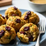 Golden brown turkey cranberry stuffing balls on a plate, garnished with herbs. Delicious holiday appetizer.